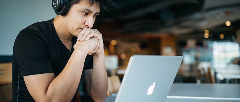 A male student sits at a desk in front of a computer 