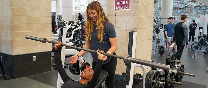 Photo of Fitness Assistant spotting a fellow student.
