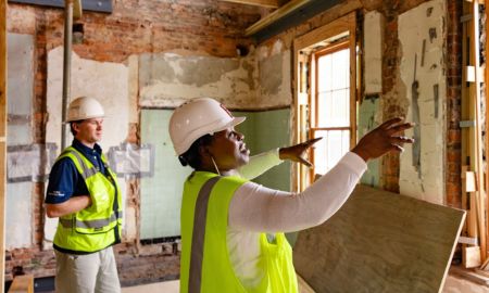 two staff members in a building, looking at construction happening