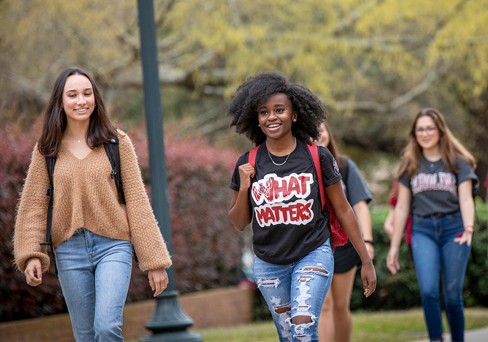 Students smiling as they are walking to class on a beautiful sunny day.