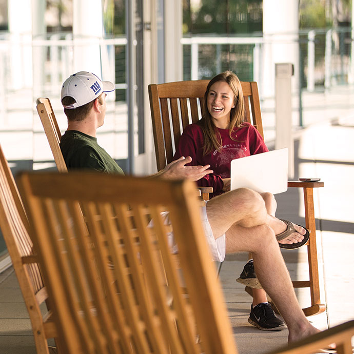 Two students sitting in rocking chairs laughing and smiling.