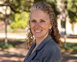 a photo of a woman smiling with a gray blazer on