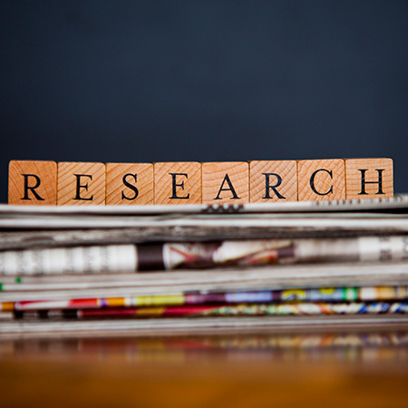 Publications stacked on a table with the word research on top in block letters.