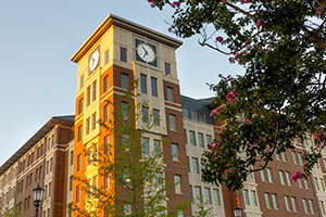 The sun shines on a clock tower on a building in the Campus Village.