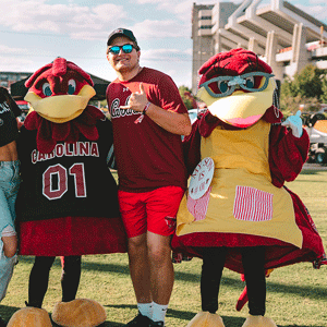 Cocky and friends stand smiling.