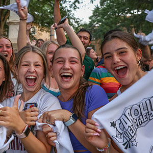 three female students smiling and cheering on the Horseshoe