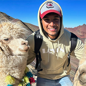 Shyam Babu poses with sheep on study away trip to Peru